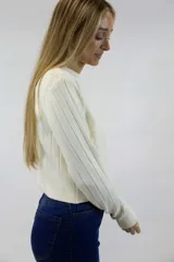 Buzo beige de tejido de punto con textura acanalada vertical, cuello redondo y mangas largas.