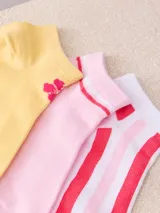 Pack de tres pares de medias de tobillo: un par amarillo con logo de flor rosa, un par rosa con dos rayas rojas en el borde y un par blanco con rayas rojas y rosas.