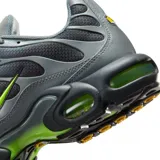 Championes Nike Air Max Plus de diseño técnico, color gris con detalles en verde neón en el logo lateral y en las unidades de aire de la suela. Presentan una estructura de malla transpirable con refuerzos sintéticos ondulados.