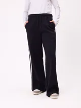 Pantalon de jogging de corte ancho, color negro con rayas laterales blancas. Posee cintura elastizada con cordón de ajuste y logo bordado en la parte frontal.