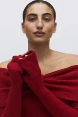 Buzo de punto acanalado color rojo, con escote off-the-shoulder y detalle de nudo frontal.