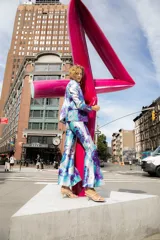 Pantalón de vestir con leve evasé y tajo en laterales, con estampado de flores grandes en tonos violeta y naranja.