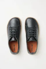 Zapatillas de cuero blanco con diseño minimalista, cordones al tono y suela de goma color suela con costura vista.