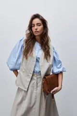 Chaleco de calce entallado color beige, de estilo cruzado con doble botonadura y escote redondo.