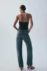 Jeans rectos de tiro medio en denim negro con efecto lavado. Presenta diseño de cinco bolsillos, trabillas para cinto y bajo con vuelta marcada. Cierre frontal con botones metálicos ocultos.