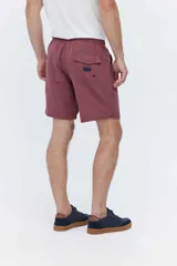 Short de baño bordó liso, de corte largo, con cintura elástica ajustable mediante cordón, bolsillos laterales y un pequeño logo estampado en el lateral.