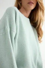 Buzo de tejido de punto en color blanco, con cuello redondo, mangas largas y corte holgado.