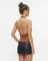 Top marrón sin mangas, con cuello halter alto y una abertura en forma de lágrima en el pecho. Cuenta con fruncidos en los laterales y cierre de botón pequeño en el cuello.