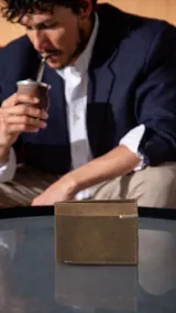 Billetera de cuero marrón con faja horizontal combinada en un tono más claro y detalle de costura en zigzag. Interior con doble repartición para billetes, visor, tarjeteros y bolsillos.