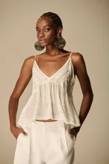 Musculosa color marfil con escote en V, tirantes finos y bordado calado con diseño geométrico. Silueta amplia y fluida.