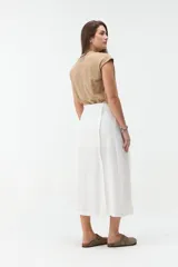 Falda midi de lino color beige, de tiro alto y corte recto, con abertura delantera y cierre cruzado sutil.