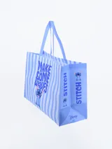 Bolsa de compras laminada con diseño de rayas verticales celestes y blancas, con estampado de Stitch y la frase "Make Some Waves".