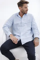 Camisa celeste a rayas verticales blancas, de manga larga y corte clásico.