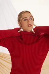 Sweater rojo de punto acanalado, con cuello alto y mangas largas.