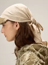 Gorro tipo pañuelo con visera rígida negra, confeccionado en lino color beige con finas rayas verticales oscuras.