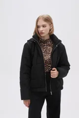 Campera negra corta de poliéster, con capucha y cierre frontal con cremallera.