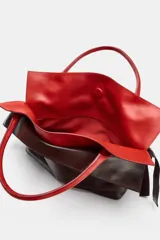 Bolso alargado de piel con doble asa de mano, diseño de doble solapa en combinación de colores y detalle de nudo en los laterales.