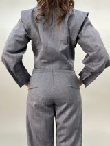 Pantalón de vestir gris con bolsillos laterales, pretina a la cintura y tablas en los bajos.