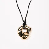 Collar con dije dorado de forma irregular y cordón negro.