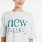 Remera de algodón color celeste claro, de corte crop y mangas cortas, con estampado gráfico de la marca New Balance en el centro del pecho.