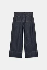 Pantalon tipo culotte de tiro alto confeccionado en denim azul oscuro. Presenta pernera ancha y corta, bolsillos delanteros de plastrón con solapa, falsos bolsillos traseros de vivo y costuras en contraste. Cierre frontal con cremallera y botón.