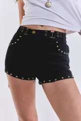 Short corto negro de gamuza con tachas doradas en el ruedo y cinturón con hebillas metálicas.