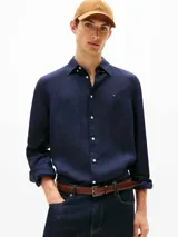 Camisa de manga larga color azul marino, confeccionada en lino pigmentado con un acabado ligeramente desgastado. Presenta cuello clásico con botones y el logo de Tommy Hilfiger bordado en el pecho.