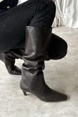 Bota bucanera de cuero color marrón oscuro con textura símil serpiente, diseño slouchy, punta fina y tacón bajo fino.