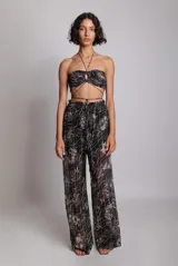 Top corto negro con estampado floral blanco, con parte delantera ajustable mediante cordones y fruncido. Tirantes elásticos y botones metálicos en la espalda.