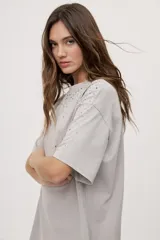 Remera oversized de manga corta y cuello redondo, de color negro con efecto acid wash y aplicación de strass en la parte superior.