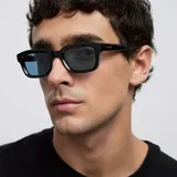 Lentes de sol con montura cuadrada de color negro y cristales polarizados en tono azul. Presentan un diseño angular y estructurado con protección UV400.