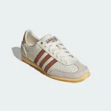Championes Adidas modelo Japan, reedición de diseño clásico de 1964. Presentan un empeine de piel perforada en color crema con las icónicas tres bandas laterales en tono marrón. Incluyen refuerzos de gamuza en la puntera y el talón, junto con una suela de goma en tono amarillento que aporta un estilo vintage.
