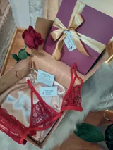 Caja de regalo artesanal color bordó con moño dorado, diseñada como experiencia de lujo para presentar un conjunto de lencería. Incluye elementos de regalo adicionales como perfume, rosa natural y dulces.