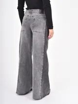Jean de corte wide leg en color gris, con diseño de paneles laterales en tono más oscuro y ruedo desflecado.