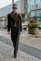 Chaqueta corta de paño en color beige, con cuello subido, manga larga y cierre frontal cruzado con botones oscuros. Presenta bolsillos delanteros de vivo.