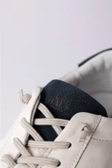 Championes urbanos de cuero blanco con suela de goma color caramelo y detalle de talón en color azul oscuro.