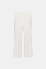 Pantalón de tiro bajo color blanco, con pernera recta y bolsillos delanteros. Cuenta con cierre frontal con cremallera, botón interior y gancho.