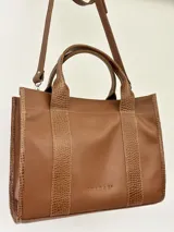 Cartera marrón de cuero genuino con doble asa corta y correa bandolera estampada con la frase "Chabas, soy real, no perfecta".