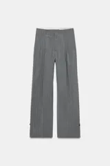 Pantalón de tiro alto con diseño de rayas verticales, corte recto y holgado. Presenta pliegues frontales, bolsillos laterales y bajo ajustable con botón.