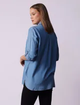 Camisa celeste de tencel con cuello con solapa, abertura central con botones ocultos, bolsillos delanteros y mangas largas regulables con presilla y botón.