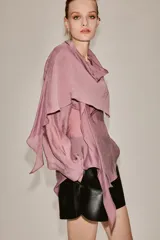 Camisa de manga larga confeccionada en mezcla de lyocell, con cuello fluido tipo pañuelo integrado, cierre frontal con botones ocultos por solapa y bajo redondeado asimétrico.