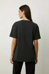 Remera de algodón color negro con cuello redondo y mangas cortas. Presenta un estampado frontal con diseño de rosas, rayos y texto, decorado con detalles de strass.