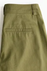 Pantalón de sarga de algodón verde militar, de tiro alto con piernas estilo barrel y costuras frontales destacadas. Cuenta con cierre de cremallera y botón oculto, bolsillos discretos en las costuras laterales y bolsillos traseros insertados.
