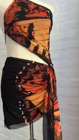 Minivestido con estampado de mariposas en tonos naranja y negro. Diseño ajustado con escote halter asimétrico y abertura en la cintura.