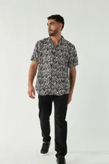 Camisa de manga corta con cuello cubano, confeccionada en viscosa con estampado de hojas en tonos azules. Presenta cierre frontal abotonado y corte slim.