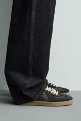 Zapatilla de estilo retro con diseño de paneles en cuero y serraje, cordones en tono crudo y suela de goma a contraste.