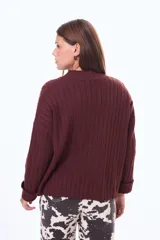 Buzo tejido de punto acanalado en color bordó, con cuello alto y mangas largas anchas con puños ajustados.