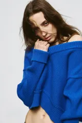 Jersey de punto color azul eléctrico con escote en pico, manga larga y detalle de costuras marcadas en los hombros. Presenta un corte ligeramente cropped con puños y ruedo acanalados.
