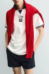 Polo de corte relajado confeccionado en piqué de algodón color blanco. Presenta cuello solapa en color negro con abertura frontal, mangas cortas con ribetes a contraste y estampado conmemorativo USA 94 FIFA World Cup.