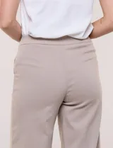 Pantalón crop blanco de corte recto con cintura ancha y botones decorativos laterales. Cuenta con bolsillos y pinzas frontales.
